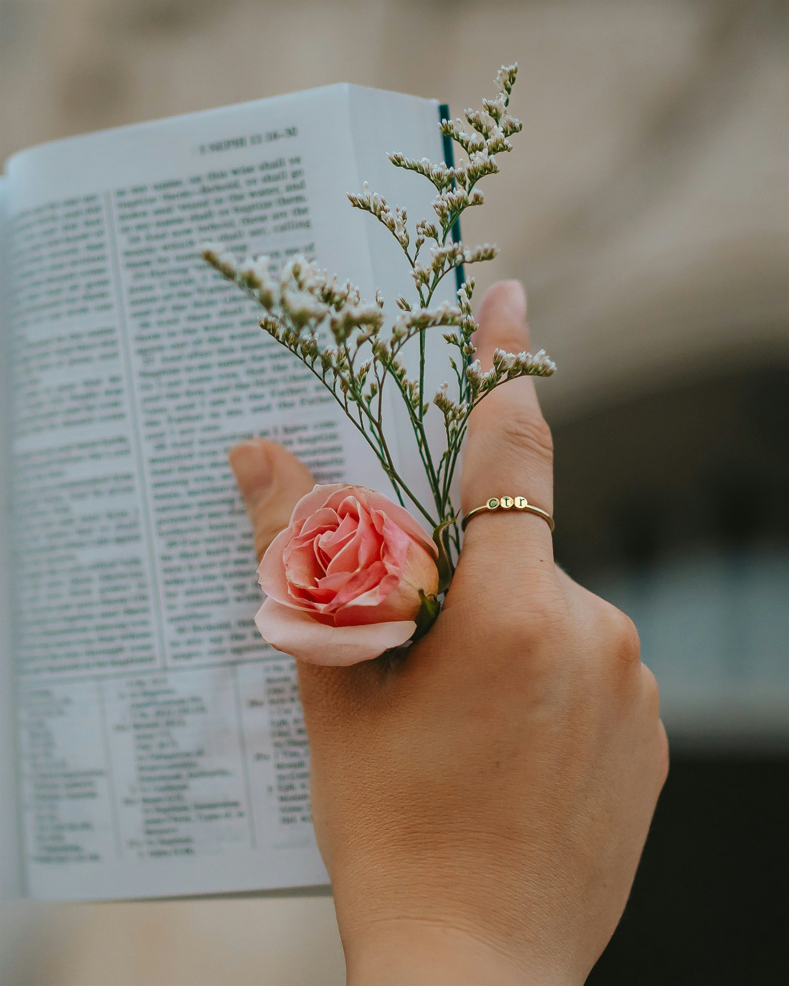 A hand holding flowers over an open Bible